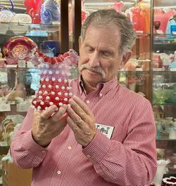 A museum presenter holding a piece of Fenton glass